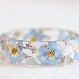 Clear resin ring with blue forget-me-not flowers and gold/copper flakes