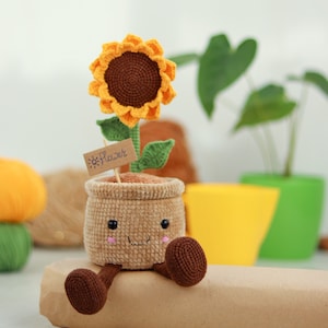 Crochet amigurumi sunflower in a pot, smiling face with brown legs and orange flower