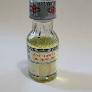 Six Flower oil perfume bottle with clear glass and amber-yellow oil, capped top