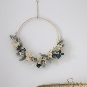 Wall circle wreath with dried preserved flowers and sage-green leaves, on a round hoop
