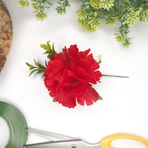 Artificial wedding boutonniere with bright red carnation flower and green leaf sprig
