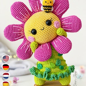 Handmade crocheted flower amigurumi toy with pink petals, yellow face, green dress, and smile