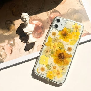 Pressed flower phone case with clear border and yellow daisies on a slim cover