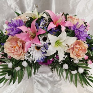 Mixed floral saddle arrangement with white lilies, purple blooms, pink and peach roses