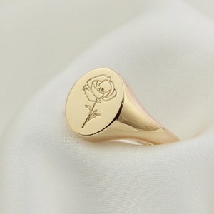 Gold-tone oval signet ring with engraved flower motif on front