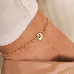 Gold lotus flower charm anklet on ankle, delicate chain with small pendant