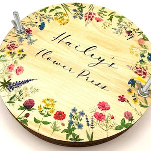 Round wooden flower press with colorful wildflower border and cursive text