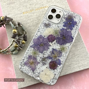 Clear iPhone phone case with purple pressed flowers and raised camera cutouts