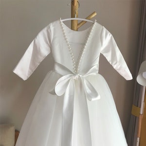 Off-white long-sleeve flower girl dress with pearl-trim V back and satin waist bow