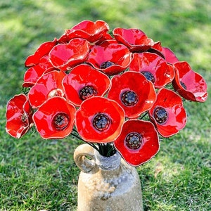 Red ceramic poppy flowers with blue centers in a small bouquet arrangement