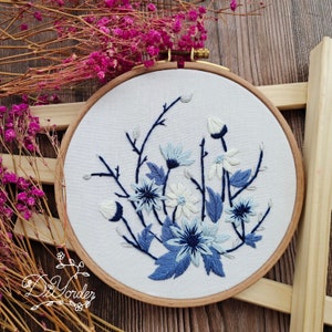 Embroidery hoop wall art with blue flower and leaf stitches on white fabric