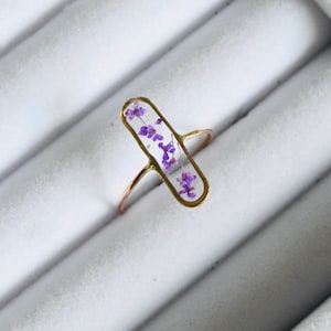 Gold-tone resin ring with oval pressed purple flower inlay