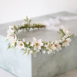 White lily-of-the-valley flower crown with small blossoms and green leaf accents
