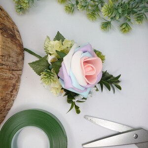 Pastel rose corsage with green leaves and soft lavender accents, for lapel or wrist