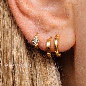 Gold-tone huggie hoop earrings with small dangling flower charm