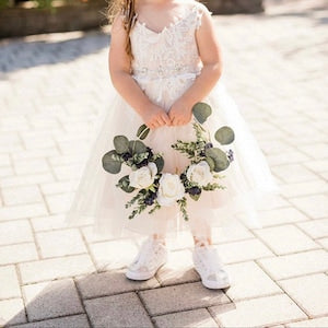 Hoop wreath bouquet with pale roses and eucalyptus greenery, held by a child