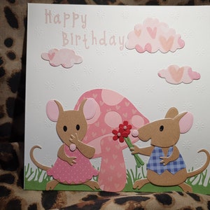 Pink birthday card with two mice holding flowers and heart-style Happy Birthday text