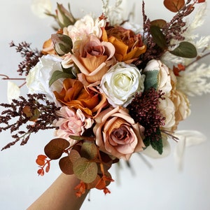 Small fall bouquet of burnt orange and ivory silk roses with brown foliage leaves