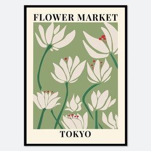 Botanical wall art print in a black frame with green leaves, white flowers, red berries, 'TOKYO' text.