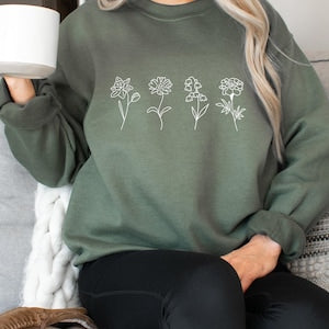 Women's dark olive green sweatshirt with white birth-flower line-art graphic