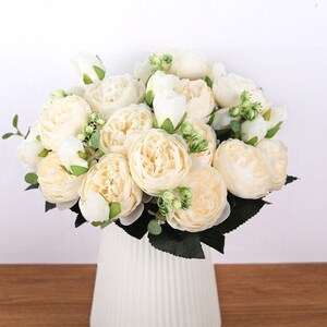 Artificial cream peony and greenery bouquet in white vase centerpiece