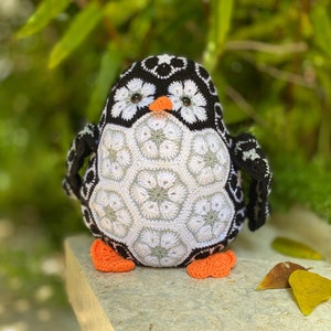 Crocheted penguin amigurumi doll with black, white, and orange feet and beak