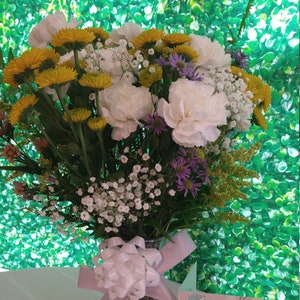 Fresh flowers bouquet with yellow blooms and pink, white, purple blossoms, wrapped with ribbon