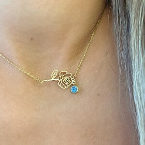 Gold-tone birth flower necklace with small flower charm and round blue gemstone