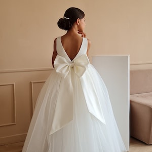 White tulle flower girl ball gown with satin bow at back and layered skirt
