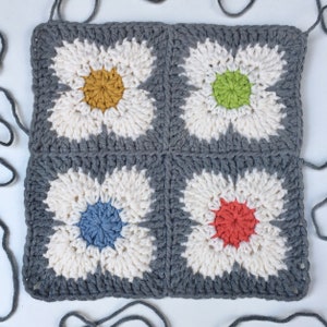 Dark gray crochet square with four daisy flowers and multicolor centers