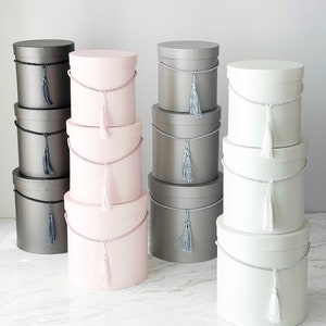 Stack of round cylindrical gift boxes with lids and tassel accents