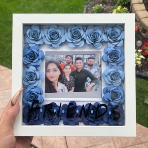 White shadow box with blue rose border and inset group photo