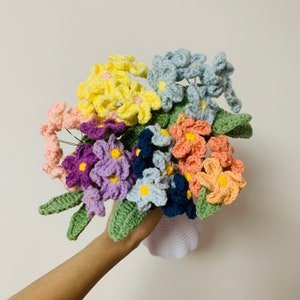 Handheld crocheted flower bouquet with blue, yellow, orange, purple blooms and green leaves