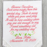 White embroidered handkerchief with pink cursive personalized wedding message and date