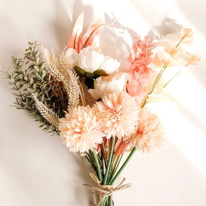Faux floral bouquet with peach and cream blooms and green foliage