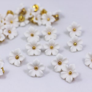 White flower shank buttons with gold-tone centers; small sakura-style floral shapes