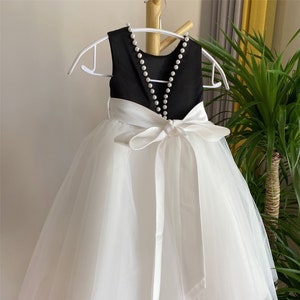 Girls communion dress with black pearl-trim bodice and off-white tulle skirt, satin bow waist