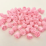 Pastel pink mini rose icing decorations, assorted rosette shapes on a flat surface