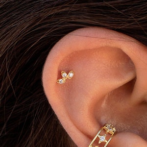 Gold-tone CZ flower/leaf stud earrings on ear