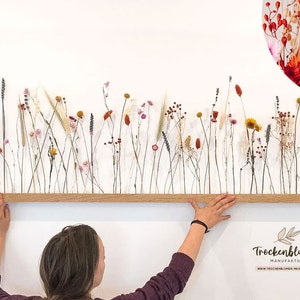 Wooden dried flower wall arrangement with slender stems and small red flowers