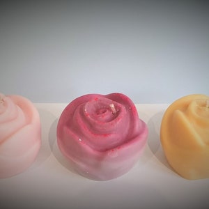 Set of three rose-shaped candles in pale pink, red-pink, and peach tones