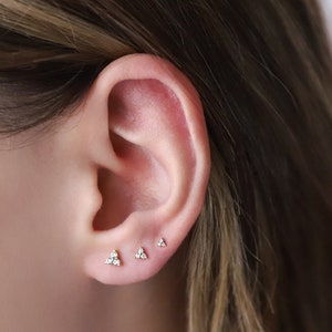 Small gold flower stud earrings on ear, 925 sterling silver