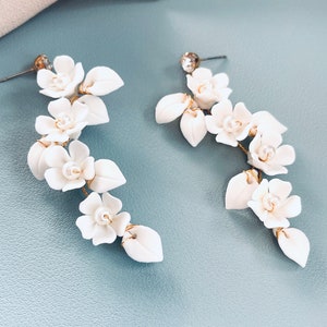 White floral chandelier earrings with small shell-like pearls and clay flower clusters