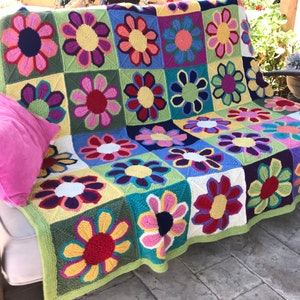Multicolor knitted blanket with repeating flower motifs and scalloped border