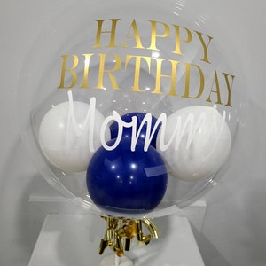 Clear birthday balloon with vinyl text "Happy Birthday Mom" and blue balloon insert