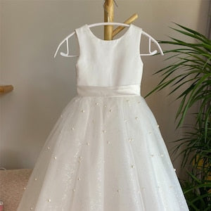 Off-white sleeveless flower girl dress with fitted bodice and sparkly tulle skirt