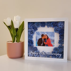White shadow box with blue rose floral frame holding a portrait photo