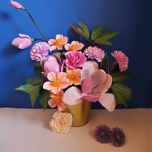 Paper flower bouquet with pink, peach, orange blooms and green leaves in a brown vase