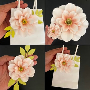 Light pink paper flower with yellow center on white stem, with green leaf accents