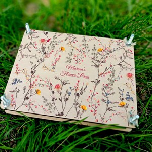 Flower press kit with floral-pattern papers and metal clamps on open frame